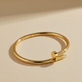 Golden nail bracelet, classic design on a white background.